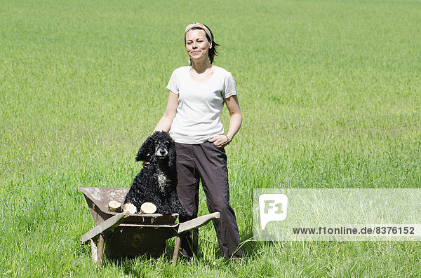 A Woman Standing In A Grass Field With Her Dog In A Wheelbarrow  Locarno  Ticino  Switzerland