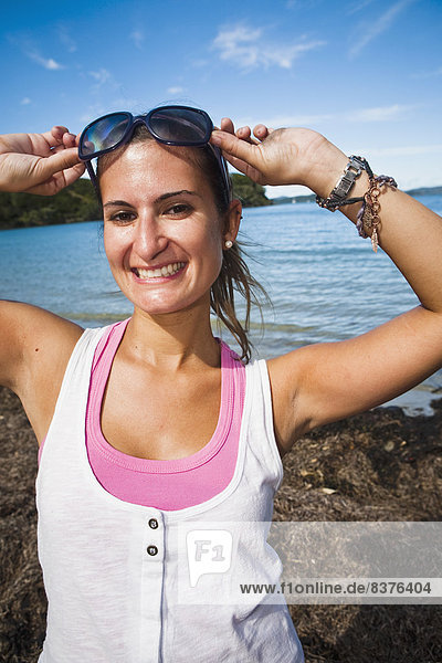 A Young Woman Poses With Sunglasses Along The Coast Of Urupukapuka Island  New Zealand