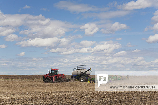 An Air Seeder In A Field With A Tractor And Blue Sky With Cloud  Acme  Alberta  Canada
