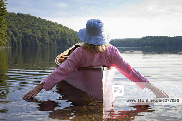 Woman In Canoe Trailing Her Hands In The Water At Algonquin Provincial Park  Ontario  Canada