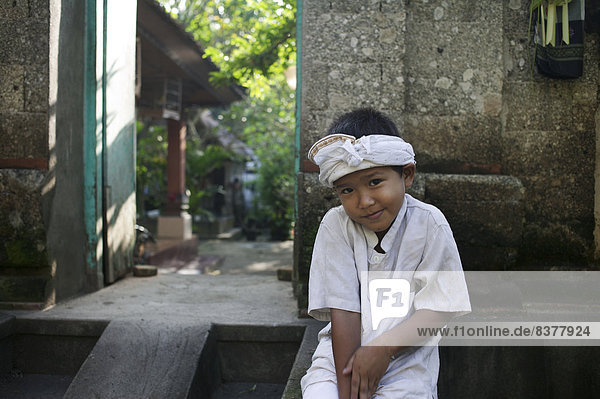 Shy Balinese Boy Sitting In Front Of A House Bali  Indonesia