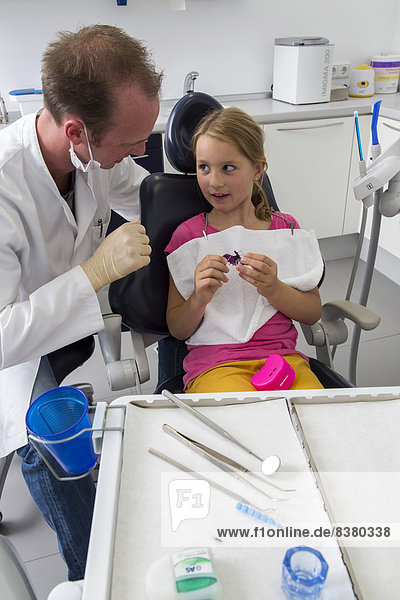 Dentist discussing further treatment with a girl and showing her braces  Germany