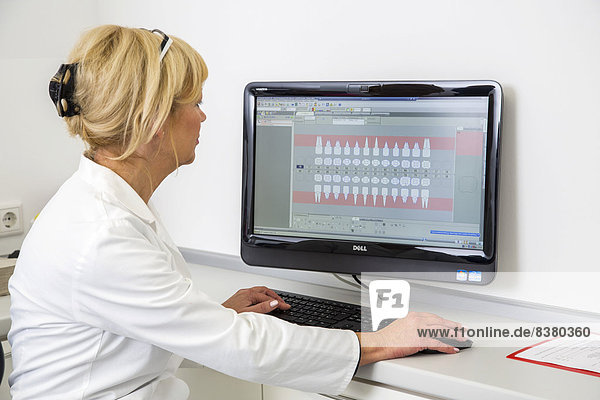 Zahnarzthelferin trägt die Daten eines Patienten in die elektronische Krankenakte ein  Deutschland