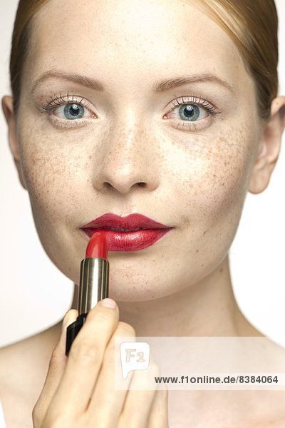 Young woman applying lipstick  portrait