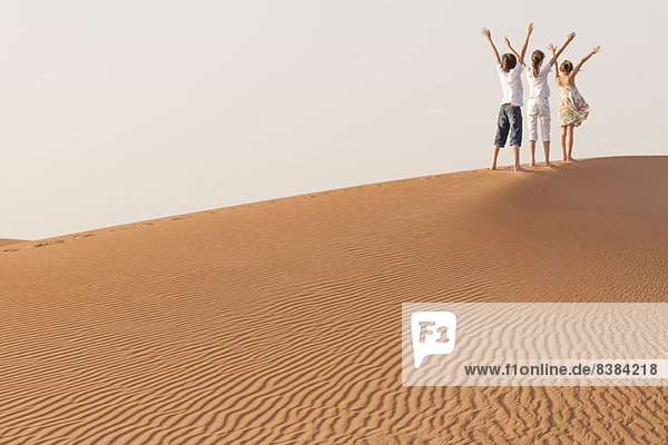 Kinder  die mit erhobenen Armen in der Wüste stehen