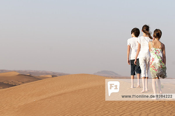 Children walking in desert  rear view