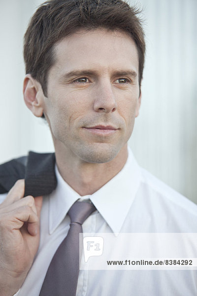 Mid-adult businessman carrying suit jacket over shoulder looking away in contemplation  portrait