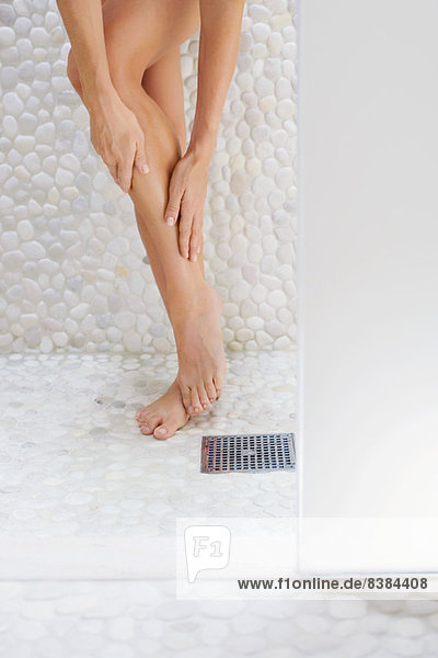 Frau im Duschraum streichelndes Bein  gestutzt