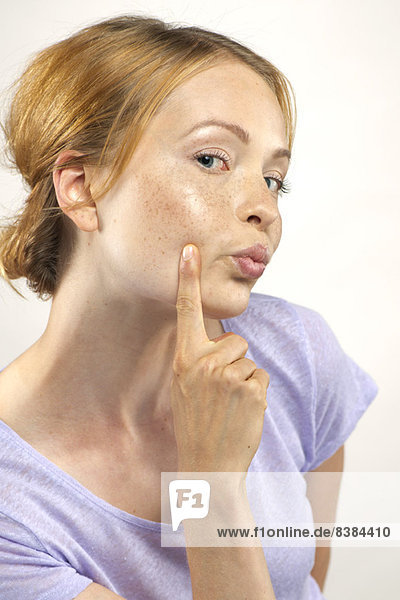 Woman puckering lips and pointing to cheek  portrait
