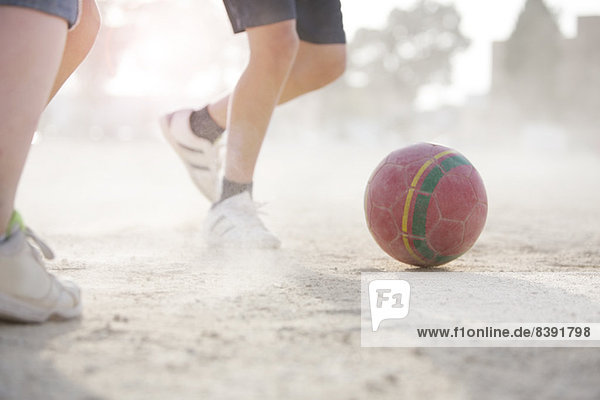 Kinder spielen mit Fußball im Sand
