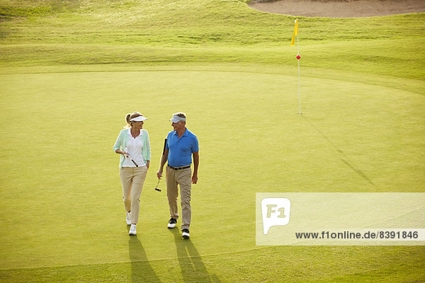 Seniorenpaar zu Fuß auf dem Golfplatz