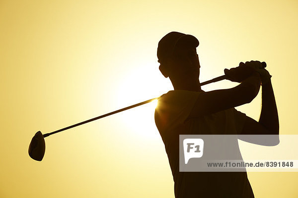Silhouette of man playing golf outdoors