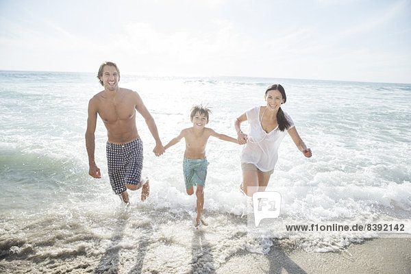 Family running in surf on beach