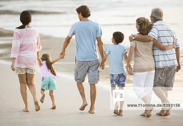 Multi-generation family holding hands on beach