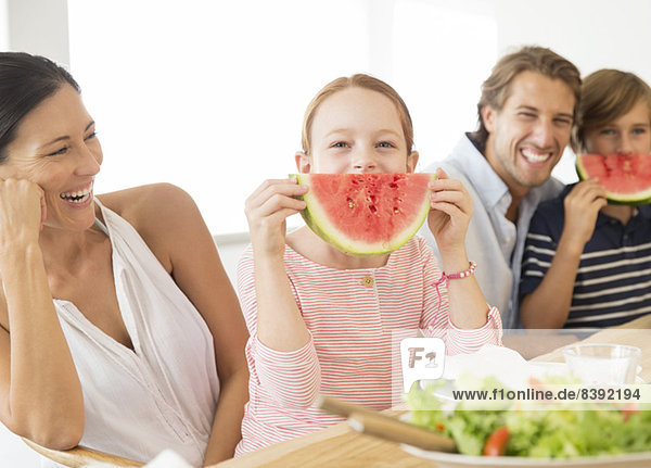 Family eating watermelon at table