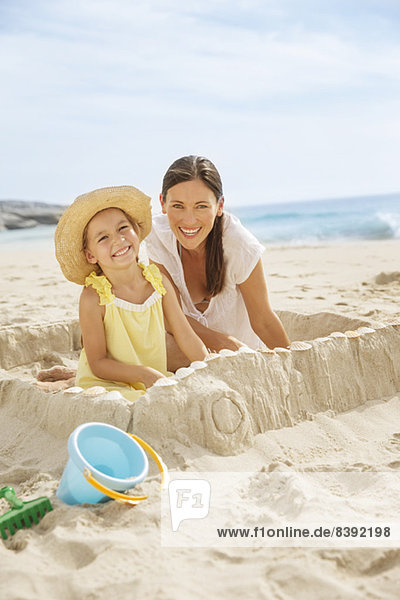 Mother and daughter making sandcastle on beach