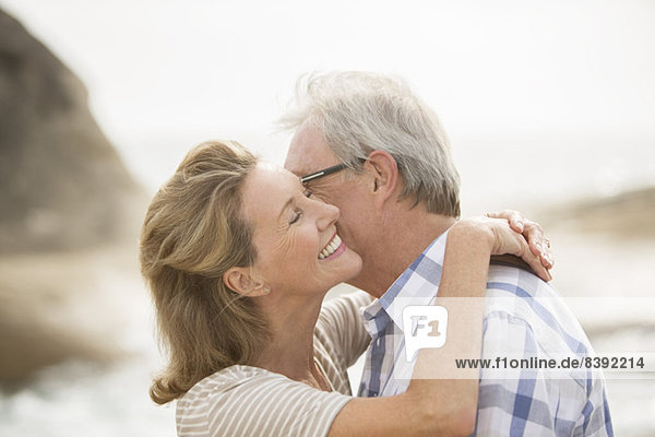 Older couple kissing on beach