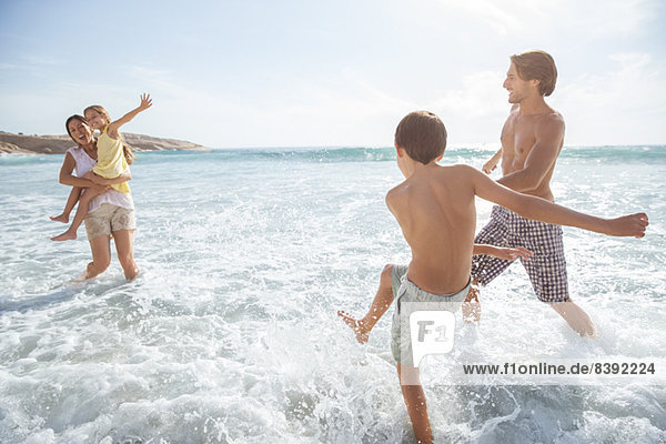 Familie spielt zusammen in Wellen am Strand