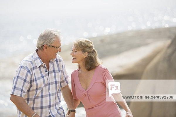 Älteres Paar hält sich am Strand an den Händen