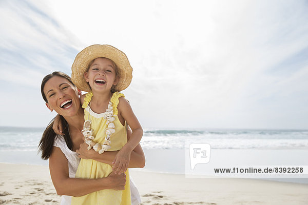 Mother and daughter laughing on beach