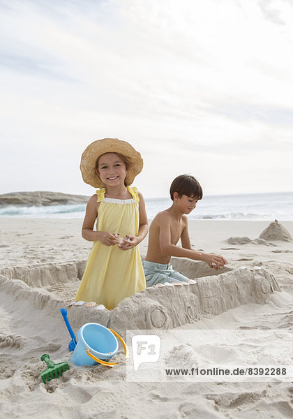 Kinder bauen Sandburg am Strand