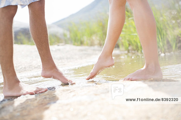 Couple dipping feet in rural pond