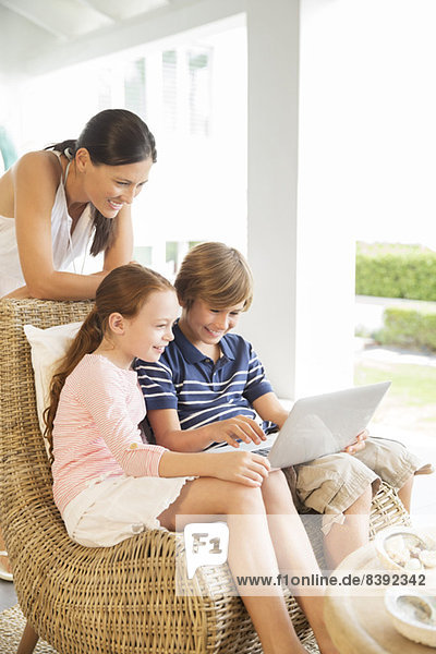Mutter und Kinder mit Laptop im Wohnzimmer