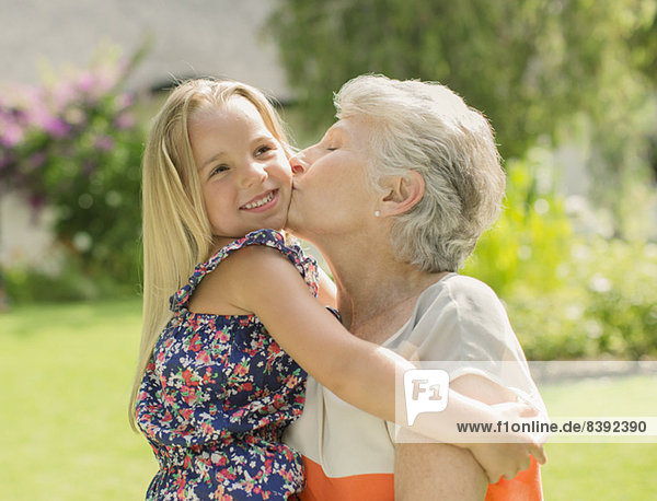 Ältere Frau küsst Enkelin im Freien