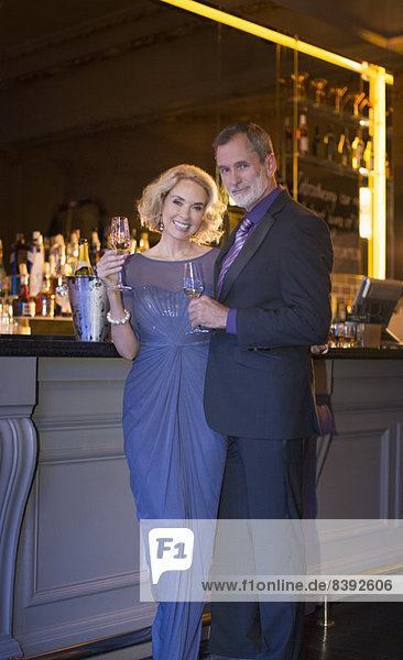 Porträt eines gut gekleideten Paares  das in einer Luxusbar Champagner trinkt.