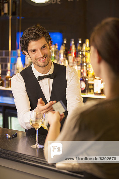 Gut gekleideter Barkeeper  der die Kreditkarte vom Kunden in der Luxusbar nimmt