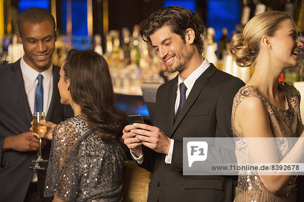 Gut gekleideter Mann mit Blick auf das Handy und einem Lächeln in der Luxusbar