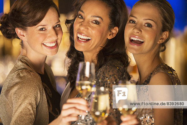 Nahaufnahme des Porträts von lächelnden Frauen beim Rösten von Champagnerflöten
