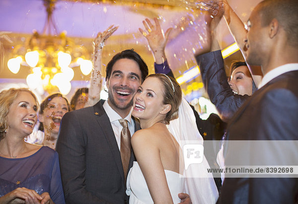 Freunde werfen Konfetti über Braut und Bräutigam bei der Hochzeitsfeier