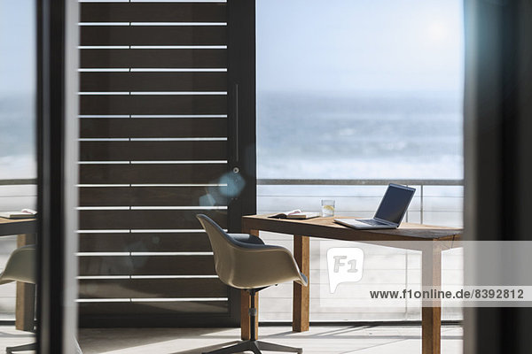 Schreibtisch und Stuhl im modernen Home-Office mit Blick auf den Ozean