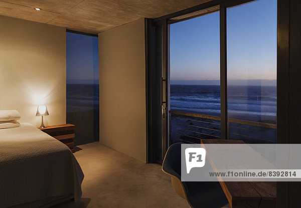 Modernes Schlafzimmer mit Blick auf das Meer in der Abenddämmerung
