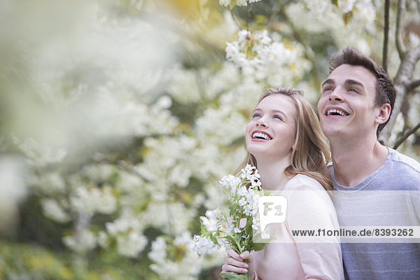 Paar lächelnd unter Baum mit weißen Blüten