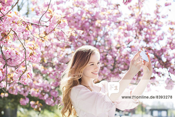 Frau beim Selbstbildnis unter Baum mit rosa Blüten