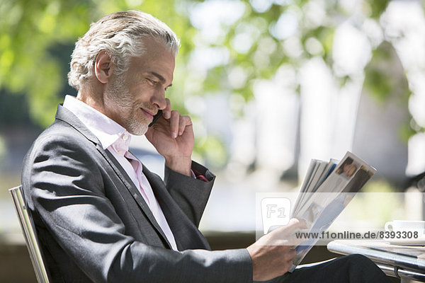 Businessman reading magazine at sidewalk cafe