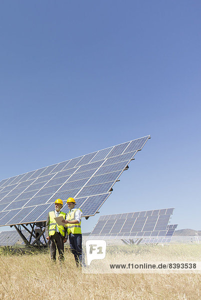 Arbeiter stehen an den Solarmodulen in der ländlichen Landschaft