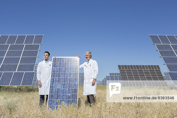 Wissenschaftler halten Solarmodul in ländlicher Landschaft