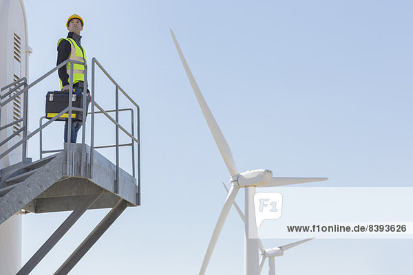 Arbeiter auf einer Windkraftanlage in ländlicher Landschaft stehend