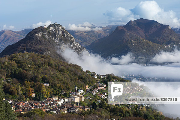 Excursion mountain of San Salvatore with the village of Cisano at the front  autumn morning with patches of fog over Lake Lugano  Monte Brè at the rear  Lugano  Canton of Ticino  Switzerland