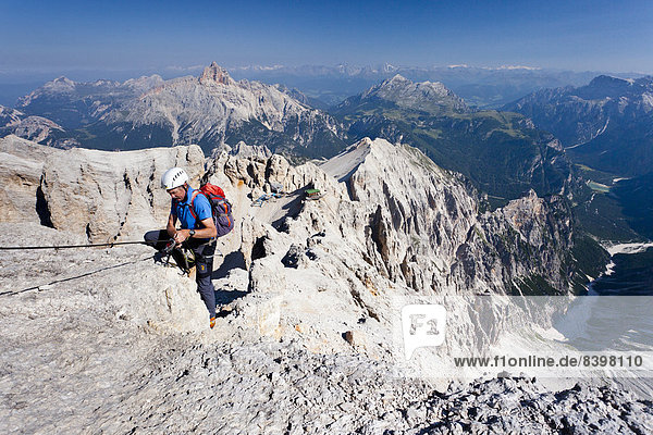 Climber on the Via Ferrata Marino Bianchi at Mt Monte Cristallo  Mt Croda Rossa or Hohe Gaisl at back  Dolomites  Belluno  Italy
