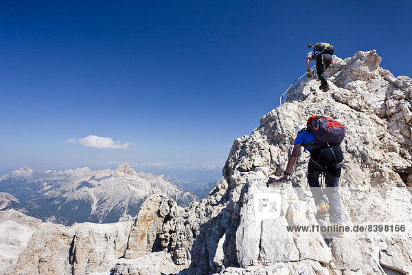 Mountain climbers climbing on the Via Ferrata Marino Bianchi climbing route on Monte Cristallo  with Croda Rossa Mountain in the distance  Dolomites  Belluno  Italy