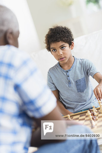 Boy playing chess with grandfather