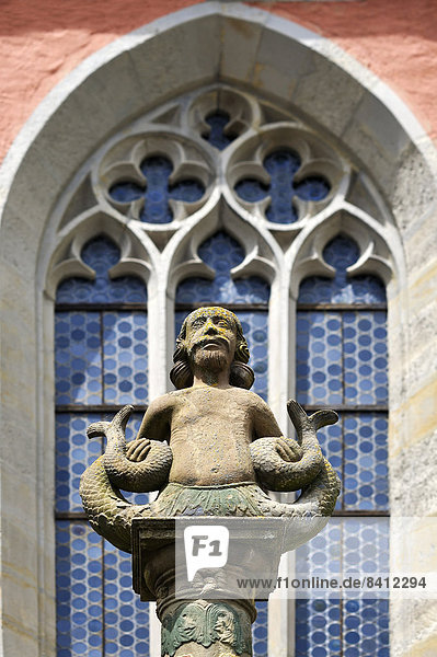 Wassermann  Skulptur auf dem Johannisbrunnen  hinten gotisches Maßwerkfenster der Johanniterkirche  14. Jhd.  Rothenburg ob der Tauber  Mittelfranken  Bayern  Deutschland
