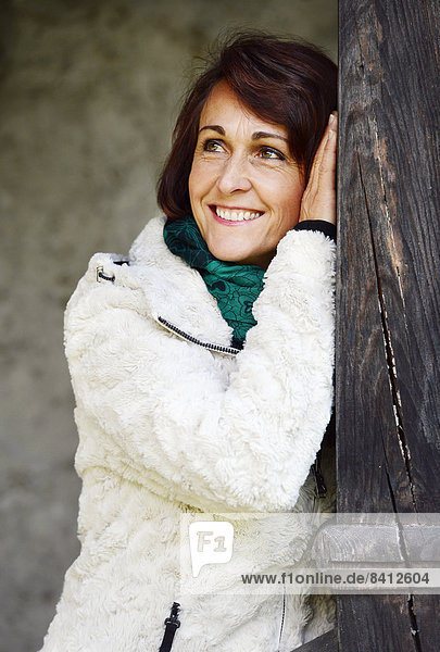 Smiling woman leaning on a wooden post