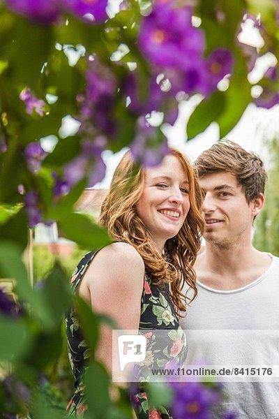 Porträt eines jungen Paares umgeben von Laub und Blumen
