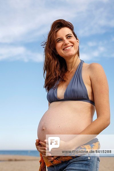 Pregnant woman on beach  hand on stomach