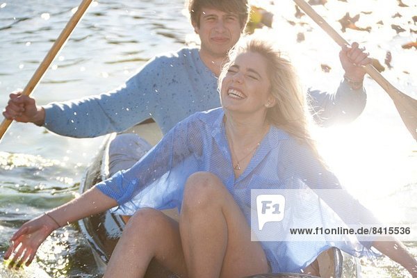Junges romantisches Paar  das mit einem Ruderboot durch die Gegend plätschert.